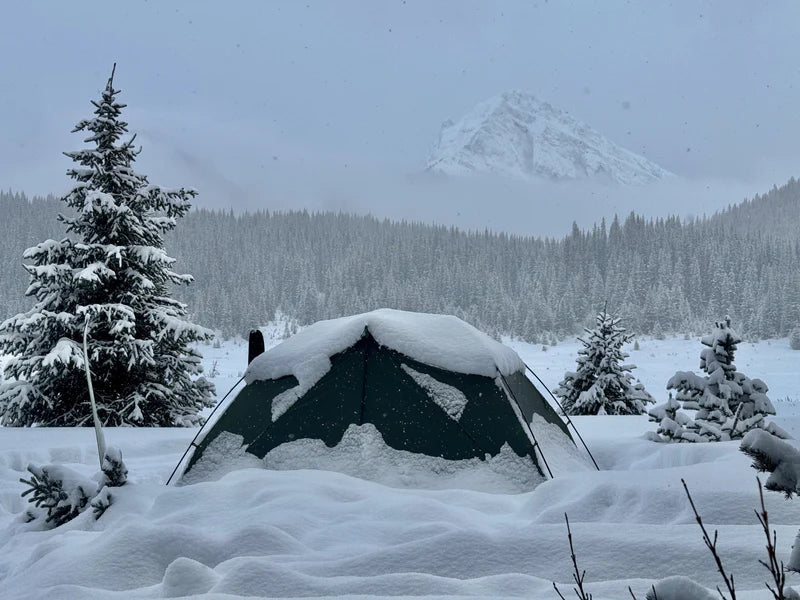 Tent covered in snow with a mountainous landscape in the background