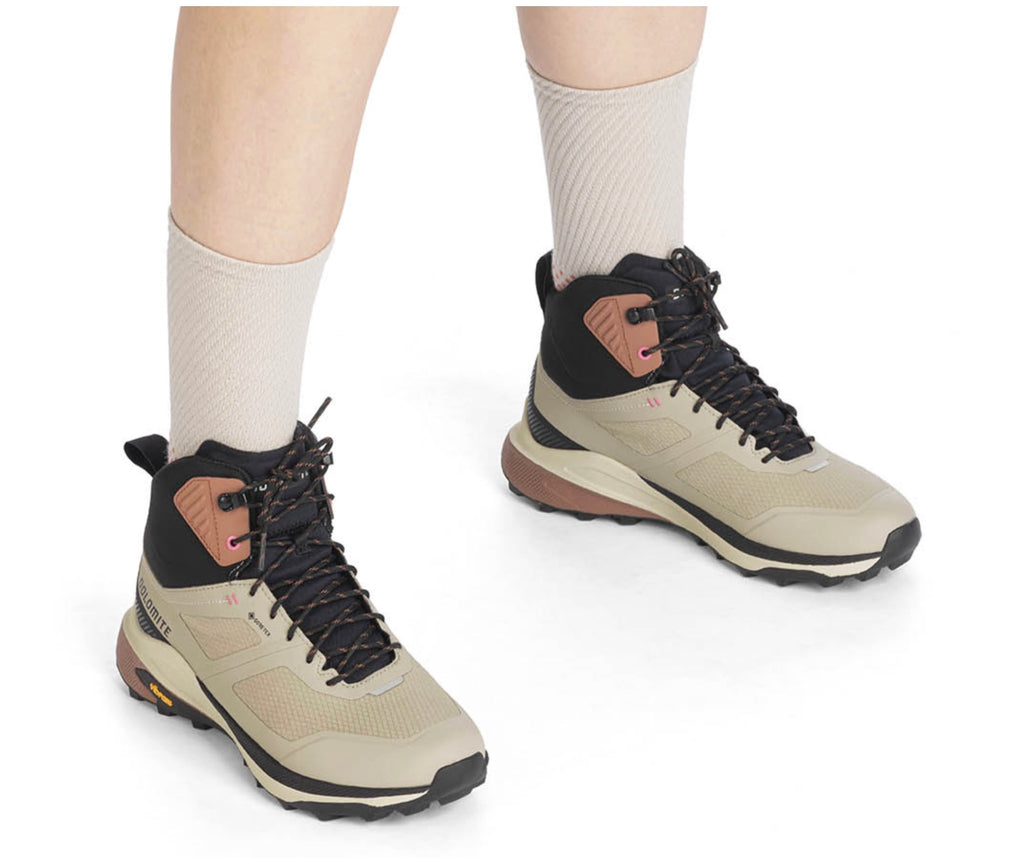 Beige hiking boots with black accents worn by a person on a white background