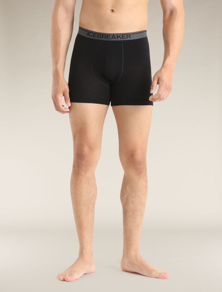 Person wearing black boxer briefs with a visible brand logo on a neutral background