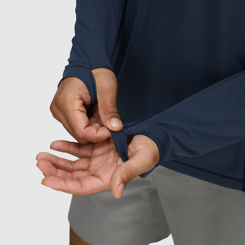 Person wearing a navy long-sleeve shirt and gray shorts, adjusting the sleeve.