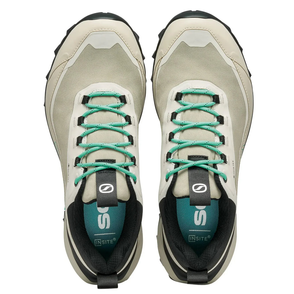 Pair of beige and black sneakers with green laces on a white background