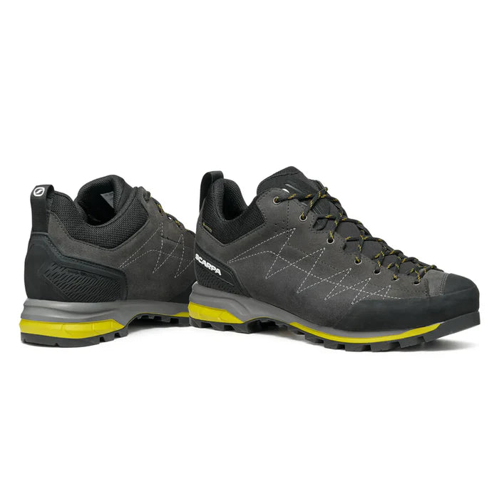 Pair of gray hiking shoes with yellow accents on a white background