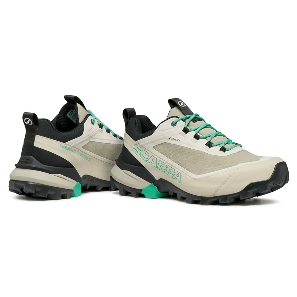 Pair of beige and black hiking shoes with green accents on a white background