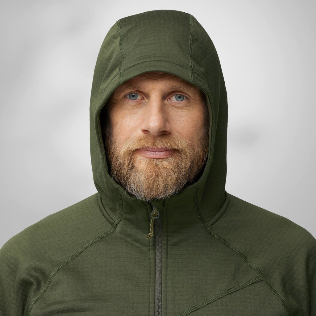 Man wearing a green hooded jacket against a plain background