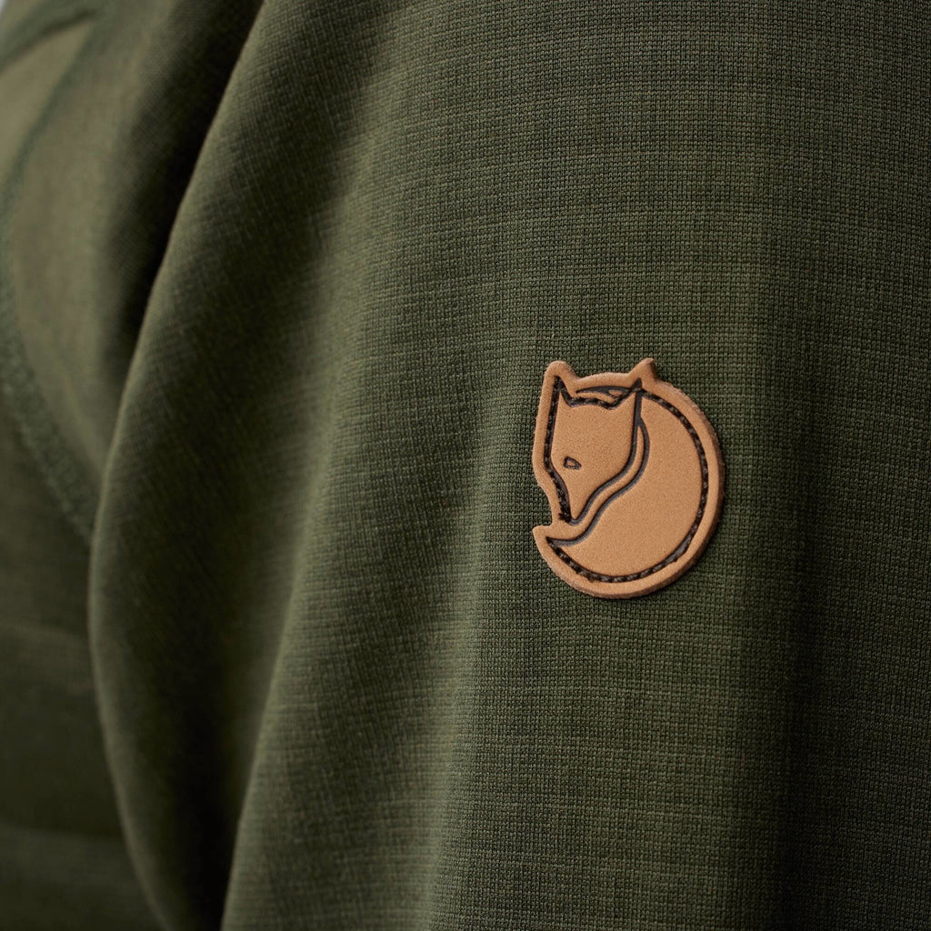 Close-up of a green jacket with a brown leather patch featuring a fox logo.