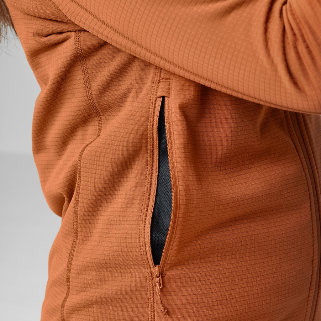 Close-up of an orange fleece with a zipper on a light gray background