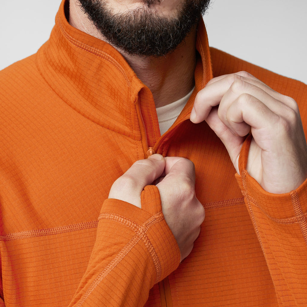 Person wearing an orange fleece with a neutral background