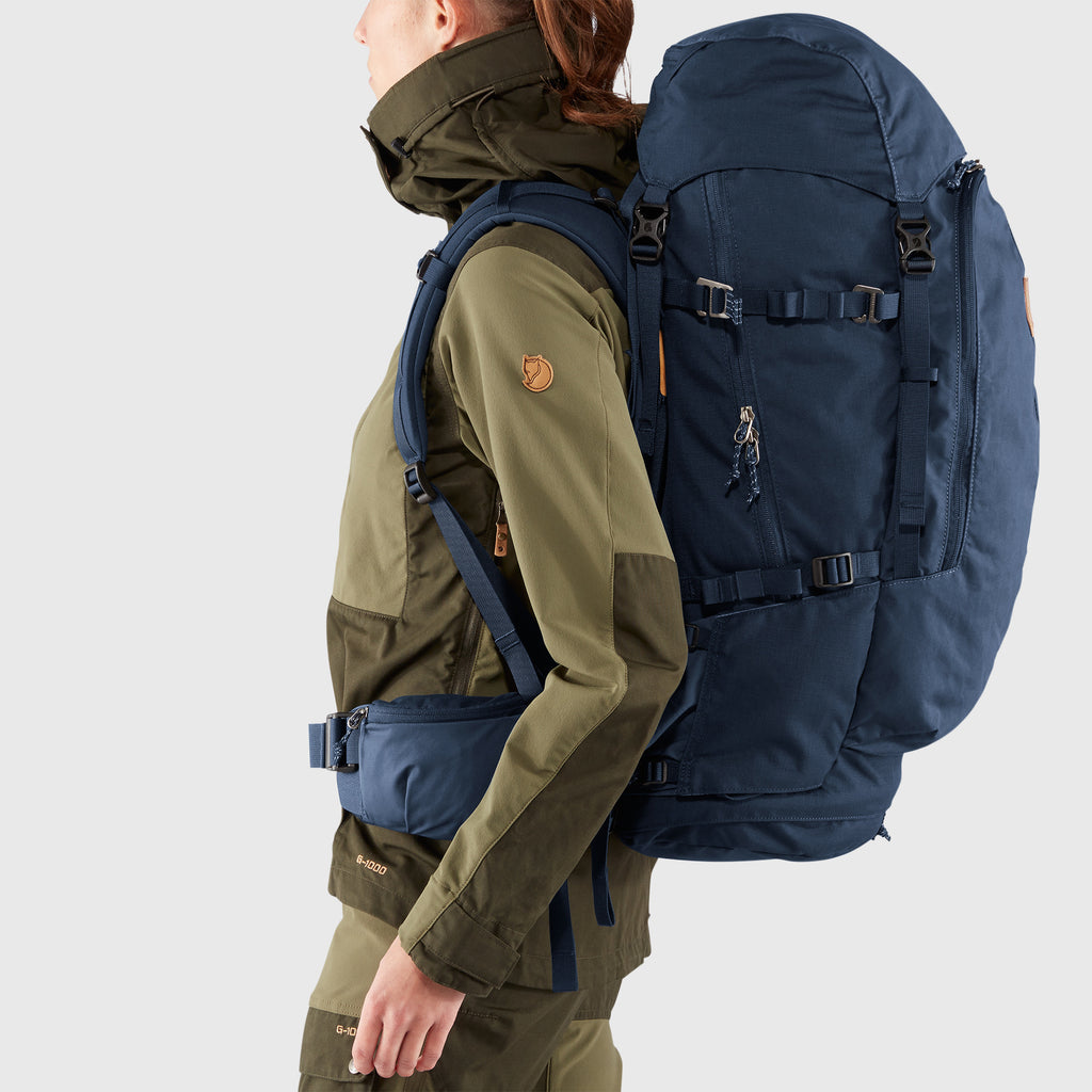 Person wearing a large blue backpack on a plain background