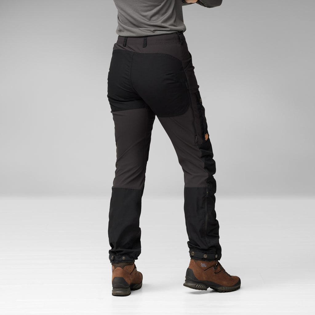 Person wearing black and gray pants with brown boots on a white background
