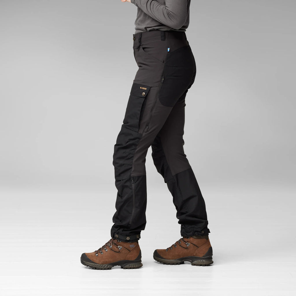 Person wearing black tactical pants with multiple pockets on a gray background