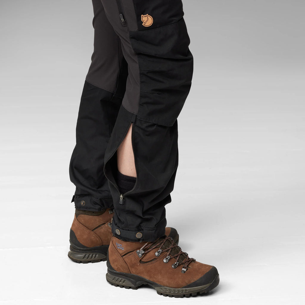 Black pants and brown hiking boots on a light gray background