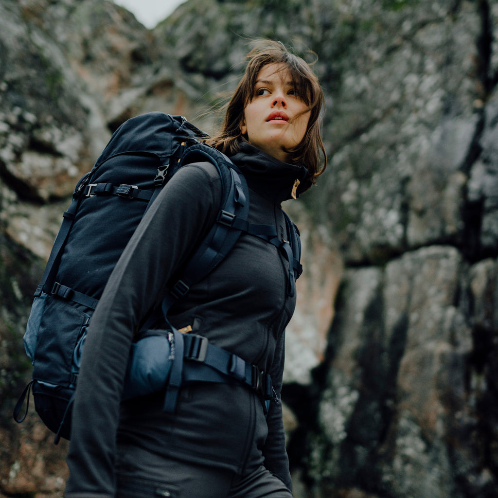 Person with a backpack standing against a rocky mountain background